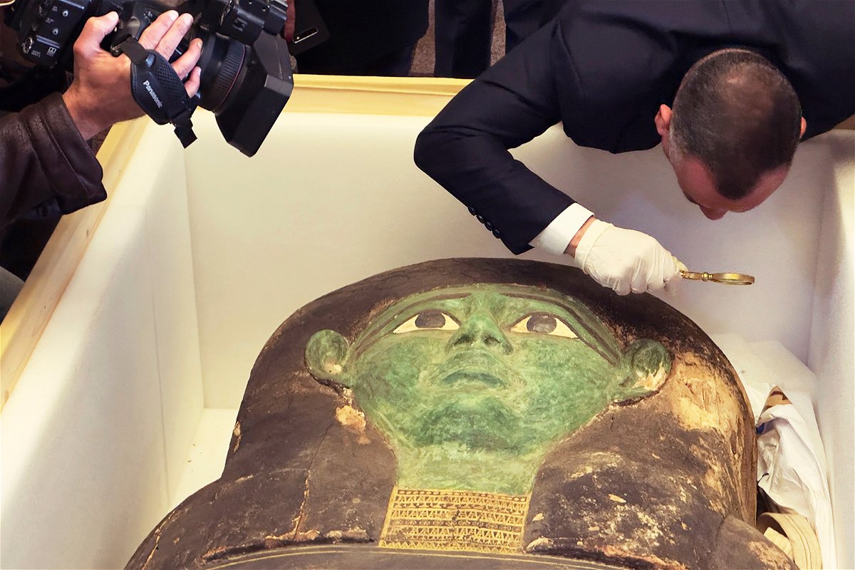 <i>Mohamed Salah/AP</i><br/>Mostafa Waziri of the Supreme Council of Antiquities takes a look with a magnifier at the ancient wooden sarcophagus during a handover ceremony at the foreign ministry in Cairo.