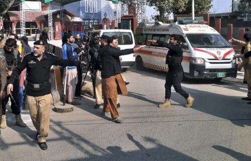 Police officers clear the route for ambulances carrying wounded people from the scene in Peshawar