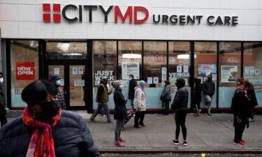 People wearing protective face masks wait in line outside a CityMD Urgent Care in the Bronx borough of New York during the COVID-19 outbreak in November 2020.