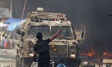 A Palestinian faces an Israeli military vehicle during a raid on the West Bank city of Nablus