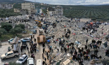 Residents search through the rubble of collapsed buildings near the Turkish border