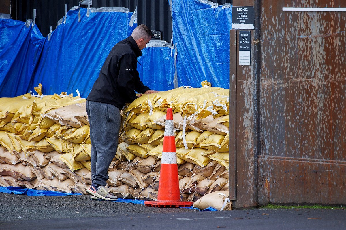 <i>David Rowland/AAP Images/Reuters</i><br/>A man stacks up sandbags to protect a warehouse before the arrival of Cyclone Gabrielle in Auckland