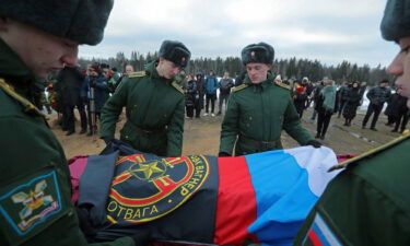 Military academy cadets cover the coffin with flags during the funeral of a Wagner Group mercenary