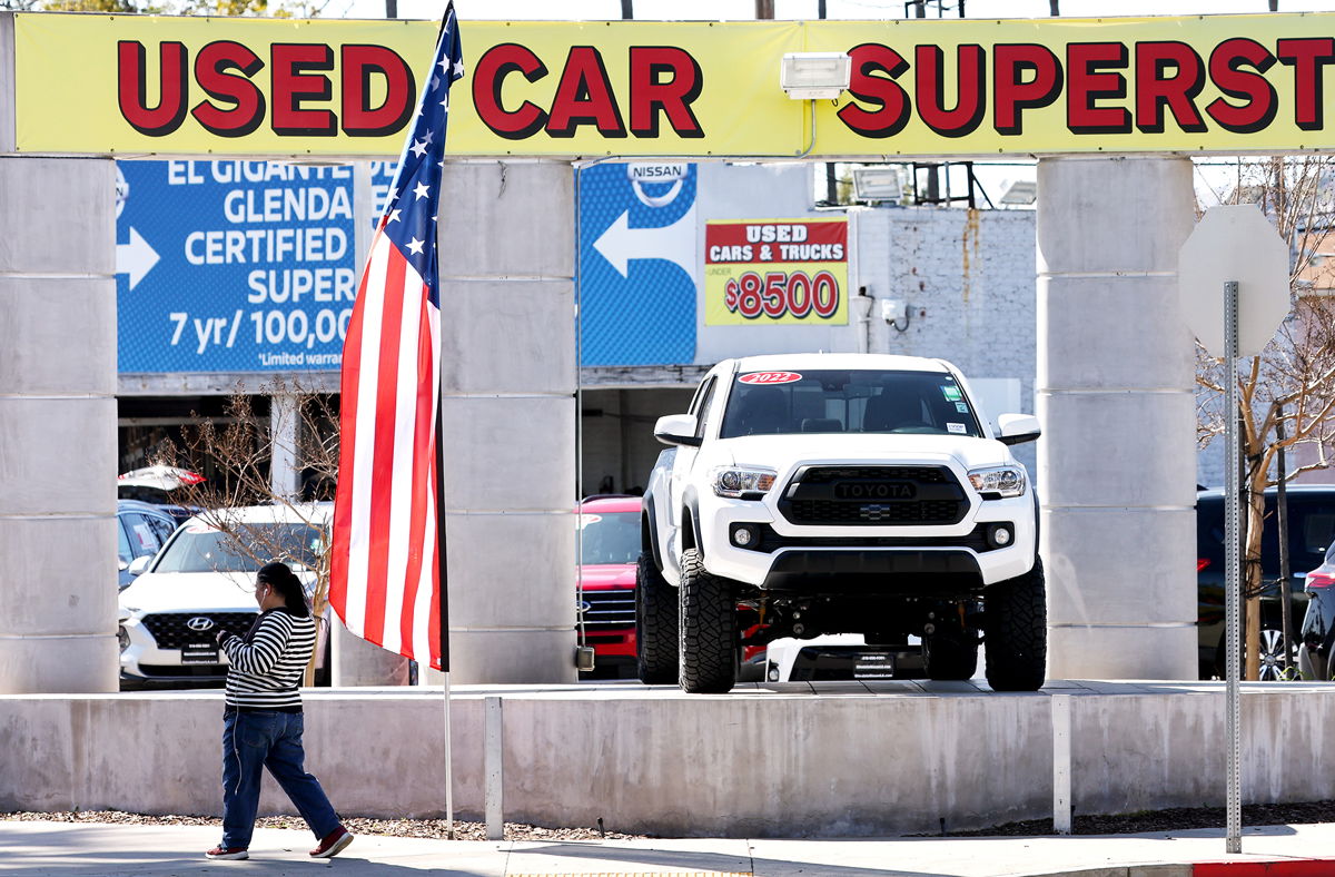 <i>Mario Tama/Getty Images</i><br/>A pedestrian walks past a used car lot on February 15 in Glendale