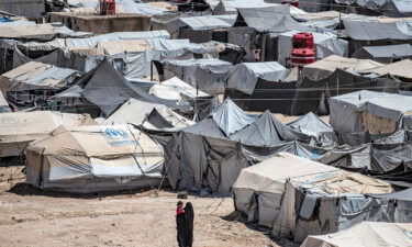 A woman walks carrying a child at the Kurdish-run al-Hol camp