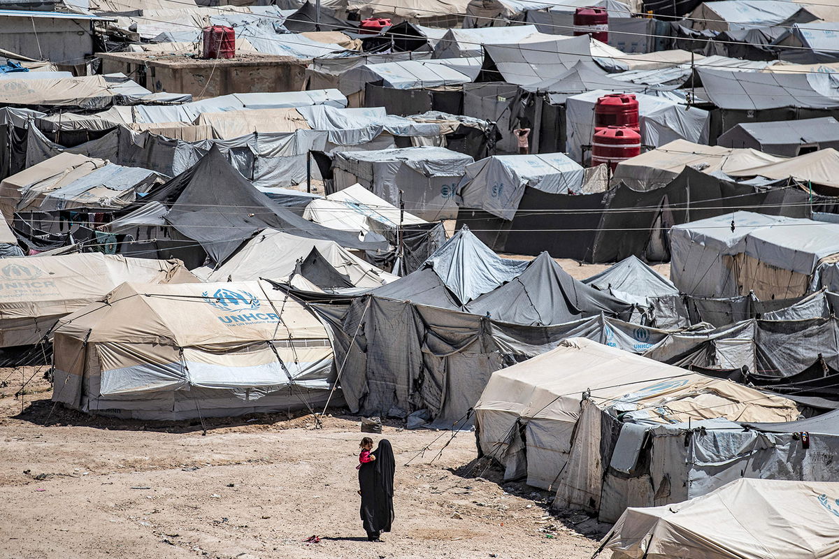 <i>Delil Souleiman/AFP/Getty Images</i><br/>A woman walks carrying a child at the Kurdish-run al-Hol camp