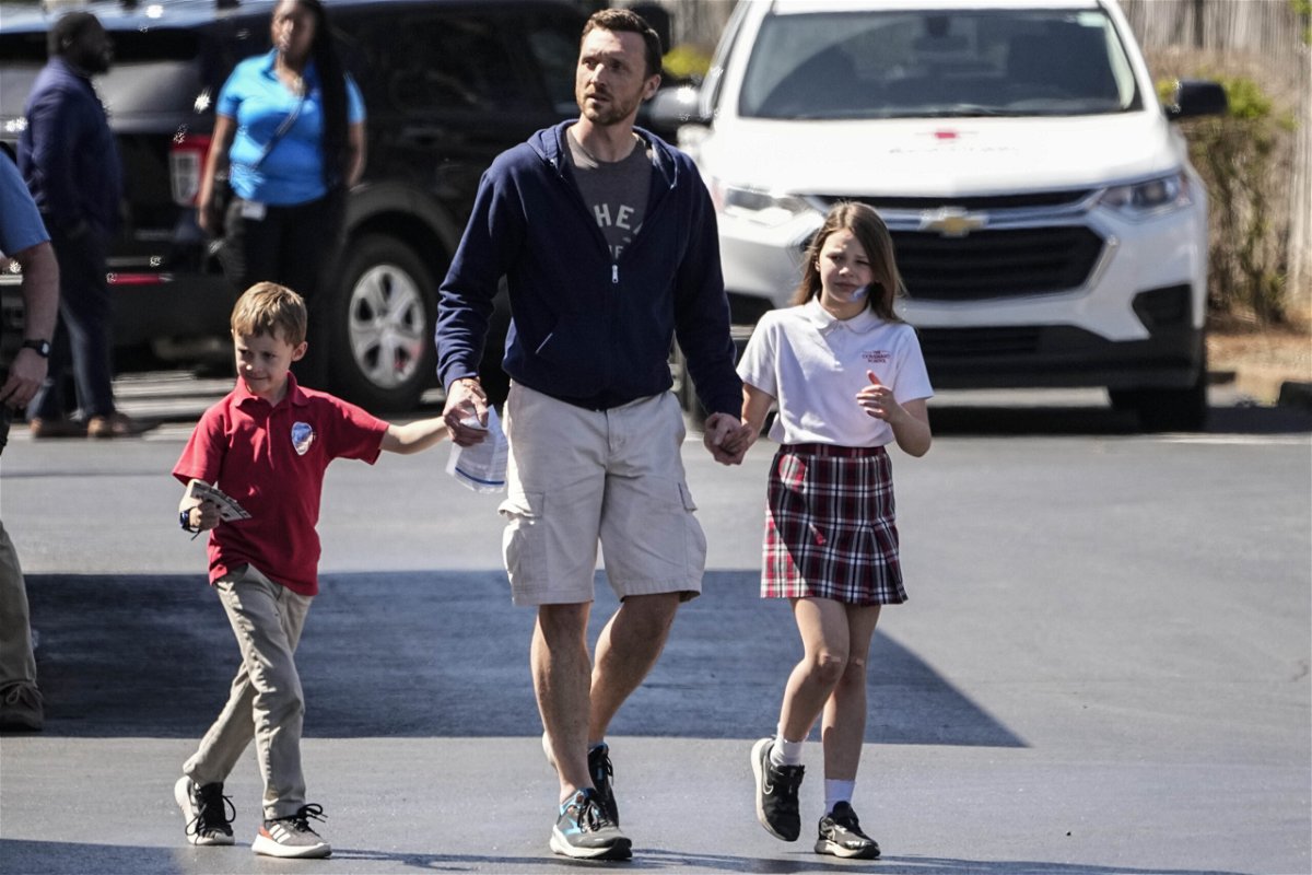 A man walks with children at the Woodmont Baptist Church after a school shooting at The Covenant School, Monday, March 27, 2023, in Nashville, Tenn. (AP Photo/John Bazemore)