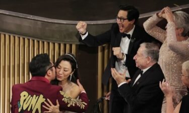 Daniel Kwan embraces Michelle Yeoh after he and Daniel Scheinert won the Oscar for best original screenplay ("Everything Everywhere All at Once").