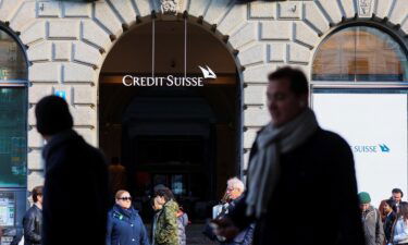 People walk near the logo of the Swiss bank Credit Suisse in Zurich