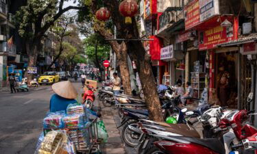 A street vendor pushes a bicycle along a road in the old quarter in Hanoi