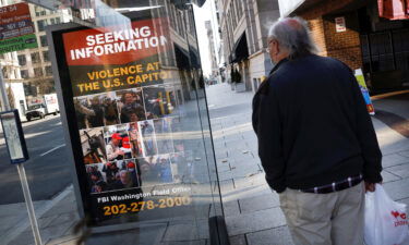 A local resident looks at a billboard with pictures of supporters of Former President Donald Trump wanted by the FBI who participated in storming the US Capitol
