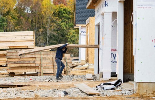 The US economy grew at a slower pace in the fourth quarter than previously estimated. A man carries siding into a house at a new home construction site in Trappe