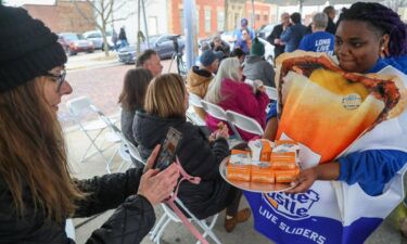 Jill Banik (left) takes a photo of Z'satrice Lott as she distributes White Castle cheeseburgers Tuesday during the last-day commemoration at the historic building in Whiting.