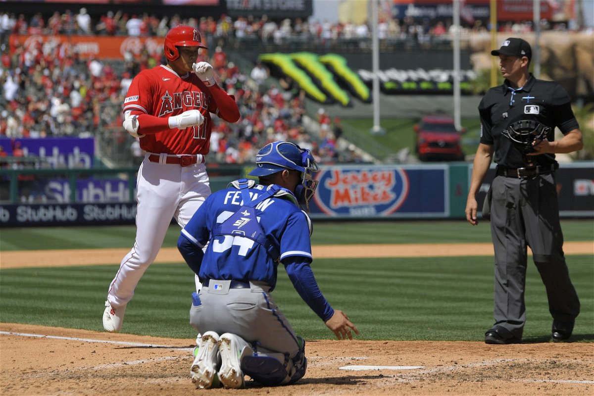 Los Angeles Angels' Shohei Ohtani, left, scores after hitting a solo home run as Kansas City Royals catch Freddy Fermin, center, and home plate umpire Shane Livensparger watch during the sixth inning of a baseball game Sunday, April 23, 2023, in Anaheim, Calif. 