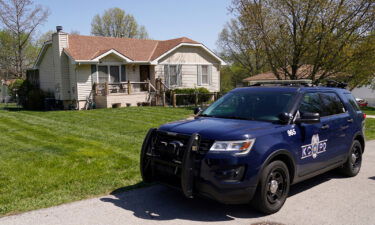 A police officer drives past the house on April 17