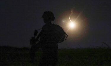 The silhouette of an Israeli soldier is outlined in the sky by a flare fired to search for a rocket that landed near Kibbutz Meitsar in the Golan Heights on April 9