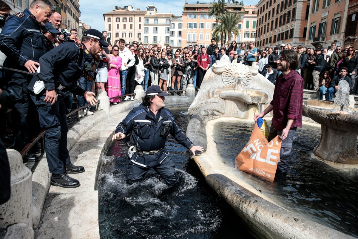 <i>Cecilia Fabiano/LaPresse/AP</i><br/>A police officer enters the fountain to remove an environmental activist.
