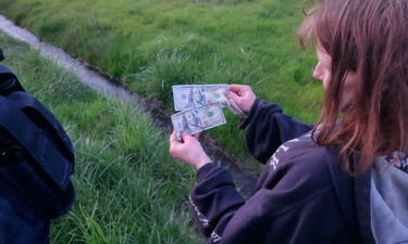 A woman holds cash on the side of Interstate-5 after a man tossed bills from his car in Oregon on April 11.