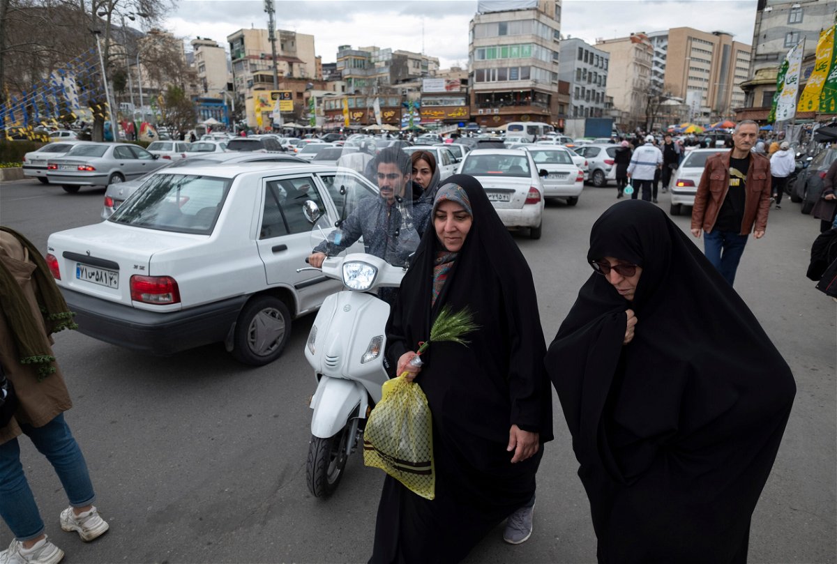 <i>Morteza Nikoubazl/NurPhoto/Getty Images</i><br/>A veiled Iranian woman walks along a square with her relative in northern Tehran on March 17.