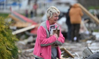 Debbie Lowdermilk holds photographs as she reacts while looking at the destroyed school she owns the day after a reported tornado hit Sullivan