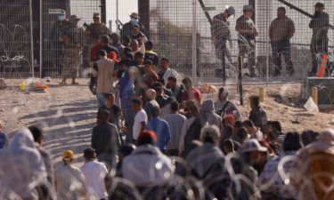 Migrants stand near the border wall after crossing the US border with Mexico near Ciudad Juarez