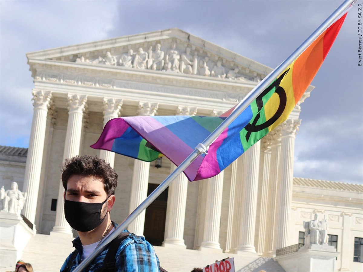 A person carries a rainbow flag in front of the Supreme Court.