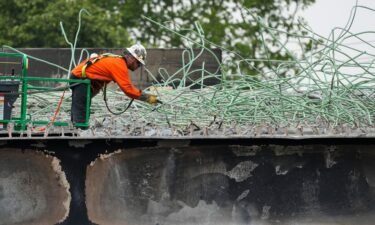 A construction worker cuts rebar at the scene of a collapsed elevated section of Interstate 95