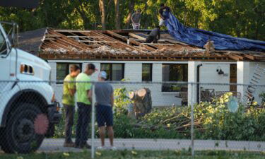 Workers put a tarp over a damaged roof after a reported tornado touched down in Johnson County