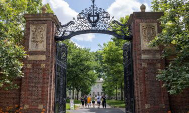 People walk through the gate on Harvard Yard at the Harvard University campus on June 29 in Cambridge