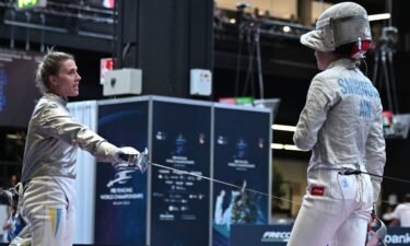 An official of the International Fencing Federation (FIE) speaks Smirnova as she sits on the fencing strip.