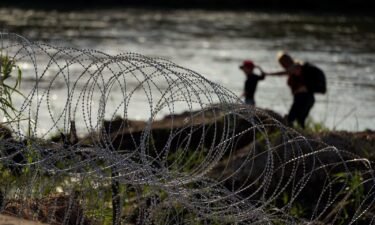 Migrants walk along concertina wire as they try to cross the Rio Grande in Eagle Pass