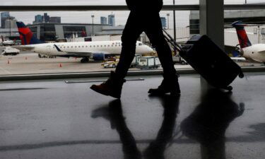 A passenger walks past a Delta Airlines plane at a gate at Logan International Airport in Boston