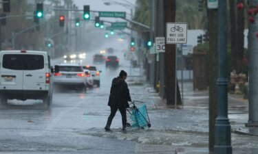 A person pushes a cart on a flooded street near Palm Springs