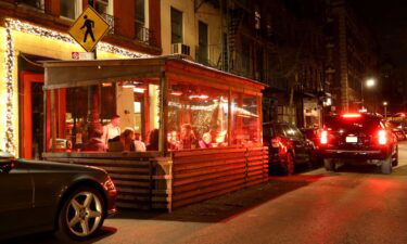 Customers sit in the outdoor dining area of a restaurant in the West Village neighborhood of New York