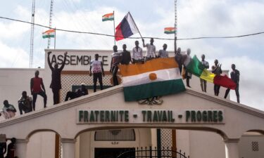 Men hold Niger and Russian flags as they gathers with thousands of anti-sanctions protestors in support of the junta in Niamey