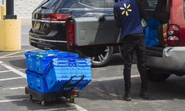 A worker delivers groceries to a customer's vehicle outside a Walmart Inc. store in Amsterdam