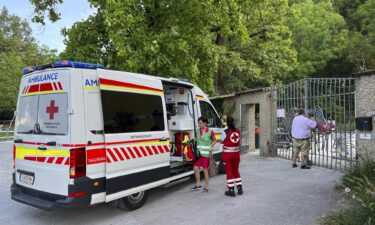 An ambulance with rescue helpers of the Red Cross stands at the entrance of the Salzburg Hellbrunn Zoo