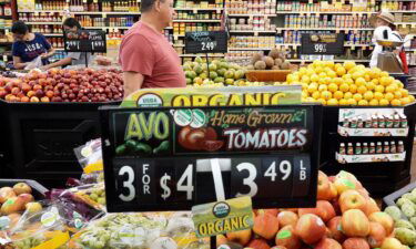 People shop in the produce section of a grocery store on September 12