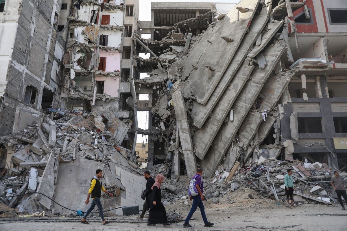 Palestinians walk through damaged buildings in Gaza City.
