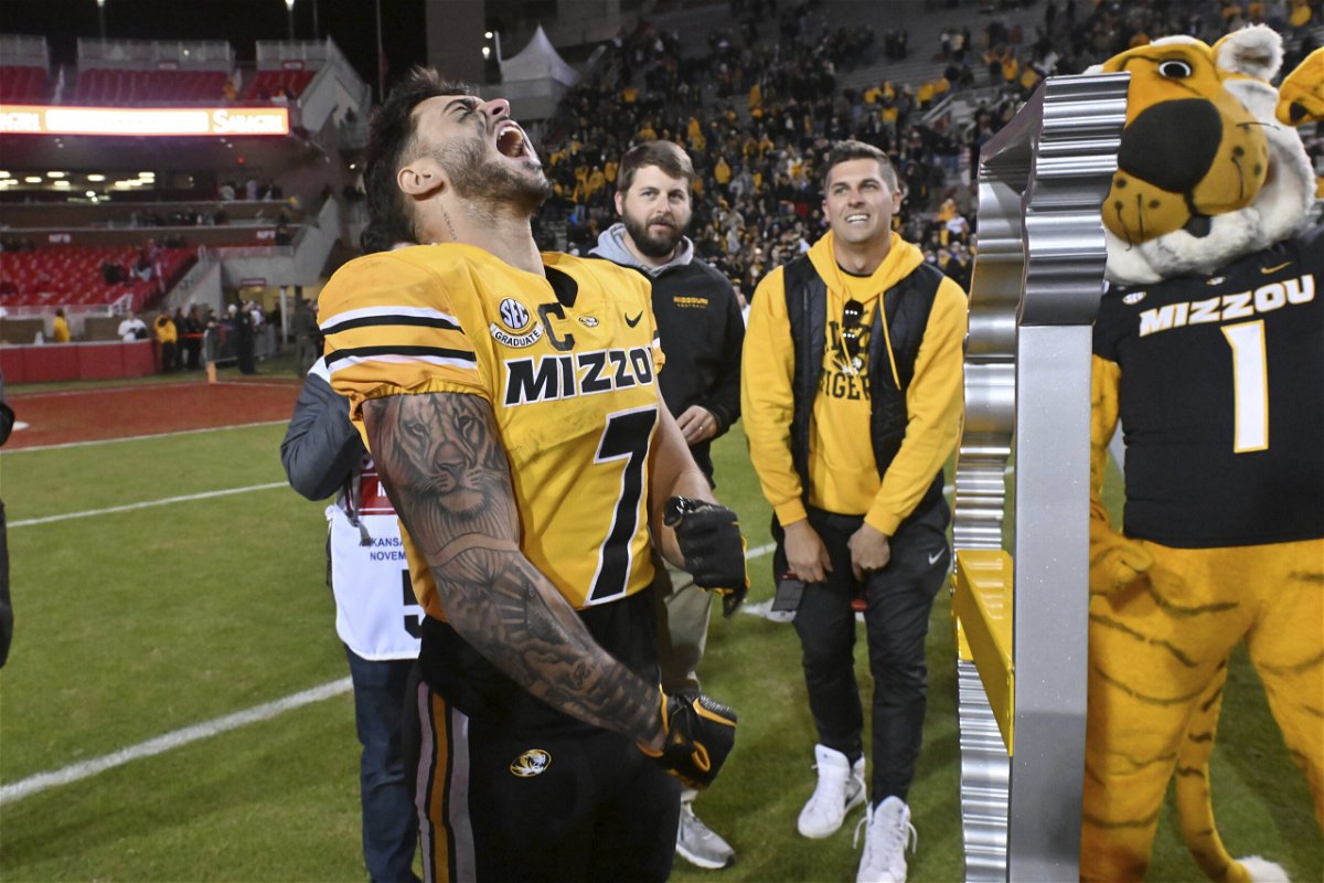 Missouri running back Cody Schrader (7) celebrates next to the Battle Line trophy after the team's win over Arkansas in an NCAA college football game Friday, Nov. 24, 2023, in Fayetteville, Ark. 