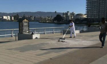 A worker cleans up the site of a destroyed menorah thrown into Lake Merritt in Oakland