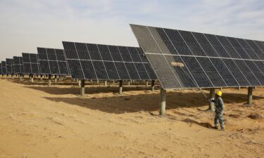 A worker cleans solar panels at a new energy base in China