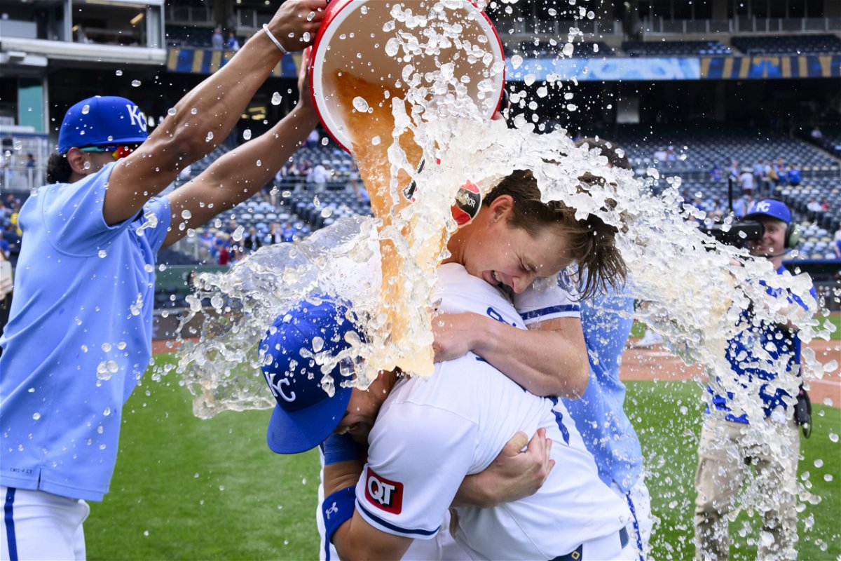 Kansas City Royals starting pitcher Brady Singer, center, without hat, hugs Bobby Witt Jr. as MJ Melendez, left, douses the two after the Royals' win against the Minnesota Twins in a baseball game Sunday, March 31, 2024, in Kansas City, Mo. 