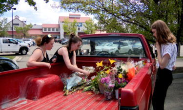 Three Lehi High School students getting flowers out of a truck bed to support the teacher who was hurt.