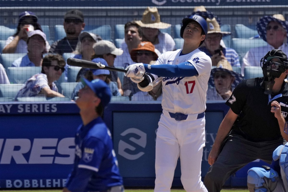 Los Angeles Dodgers' Shohei Ohtani, center, hits a solo home run as Kansas City Royals starting pitcher Brady Singer, left, and home plate umpire Ryan Additon watch during the sixth inning of a baseball game Sunday, June 16, 2024, in Los Angeles. 