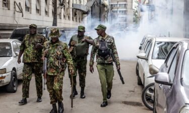 Kenya police officers walk away from a street covered in tear gas during a demonstration against tax hikes in downtown Nairobi