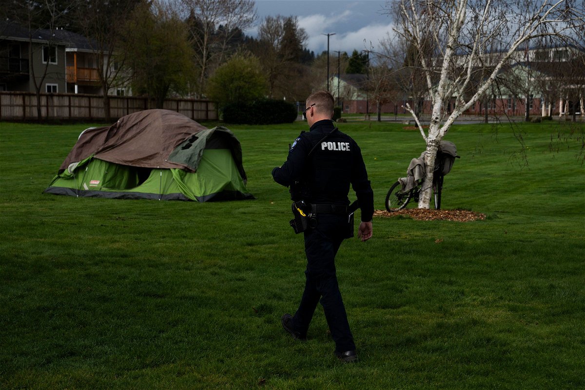 A police officer walks to check on a homeless person on March 23, in Grants Pass, Oregon.
