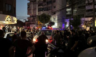 People gather near a site hit by what security sources said was a strike on the southern suburbs of Beirut