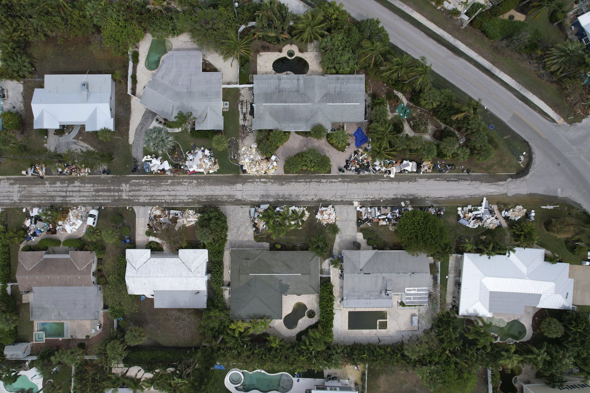 In this image taken with a drone, piles of furniture and household items destroyed in Hurricane Helene flooding sit piled up outside of homes ahead of the arrival of Hurricane Milton, Tuesday, Oct. 8, 2024, in Holmes Beach on Anna Maria Island, Fla.