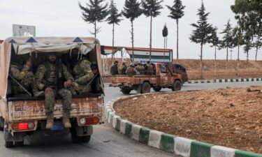 Rebel fighters sit on a vehicle in Homs